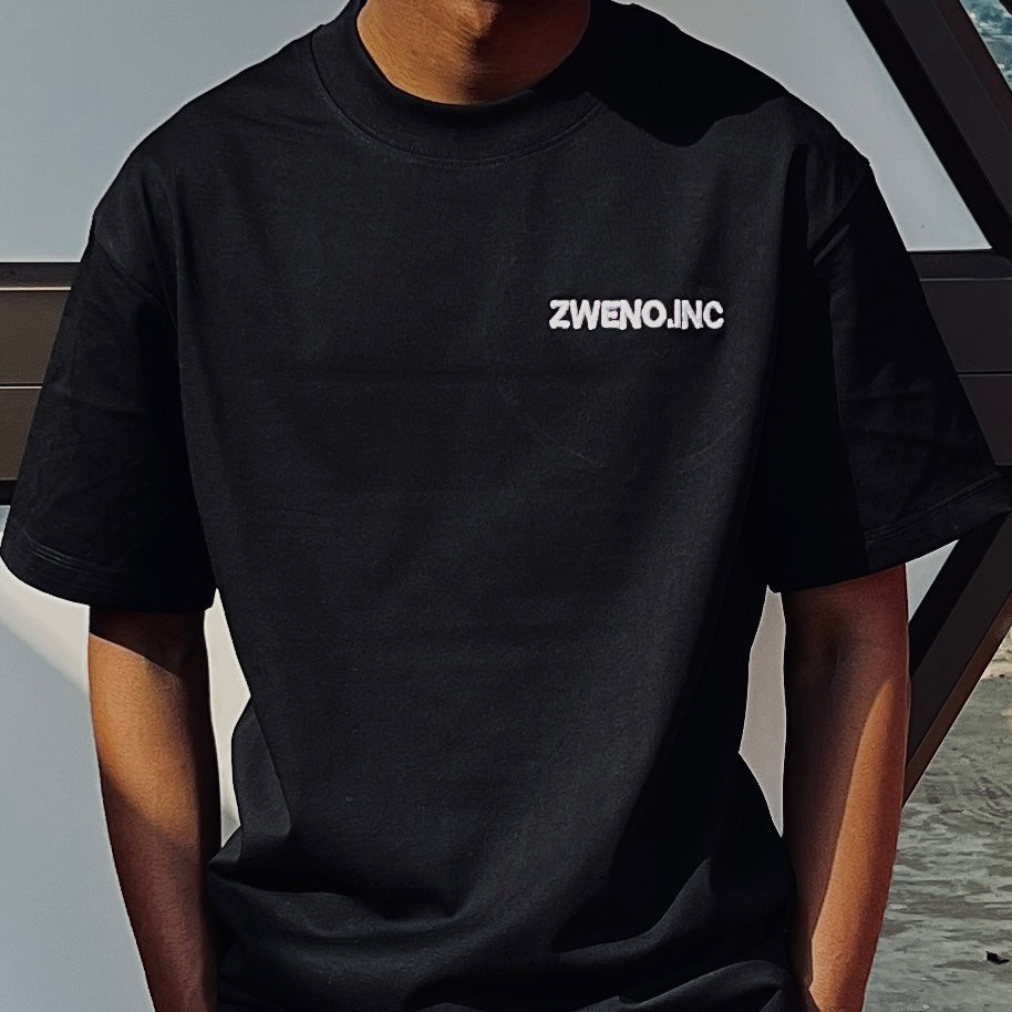 ZWENO.INC black cotton short sleeve t-shirt with white minimalist logo on the chest, worn by a person.